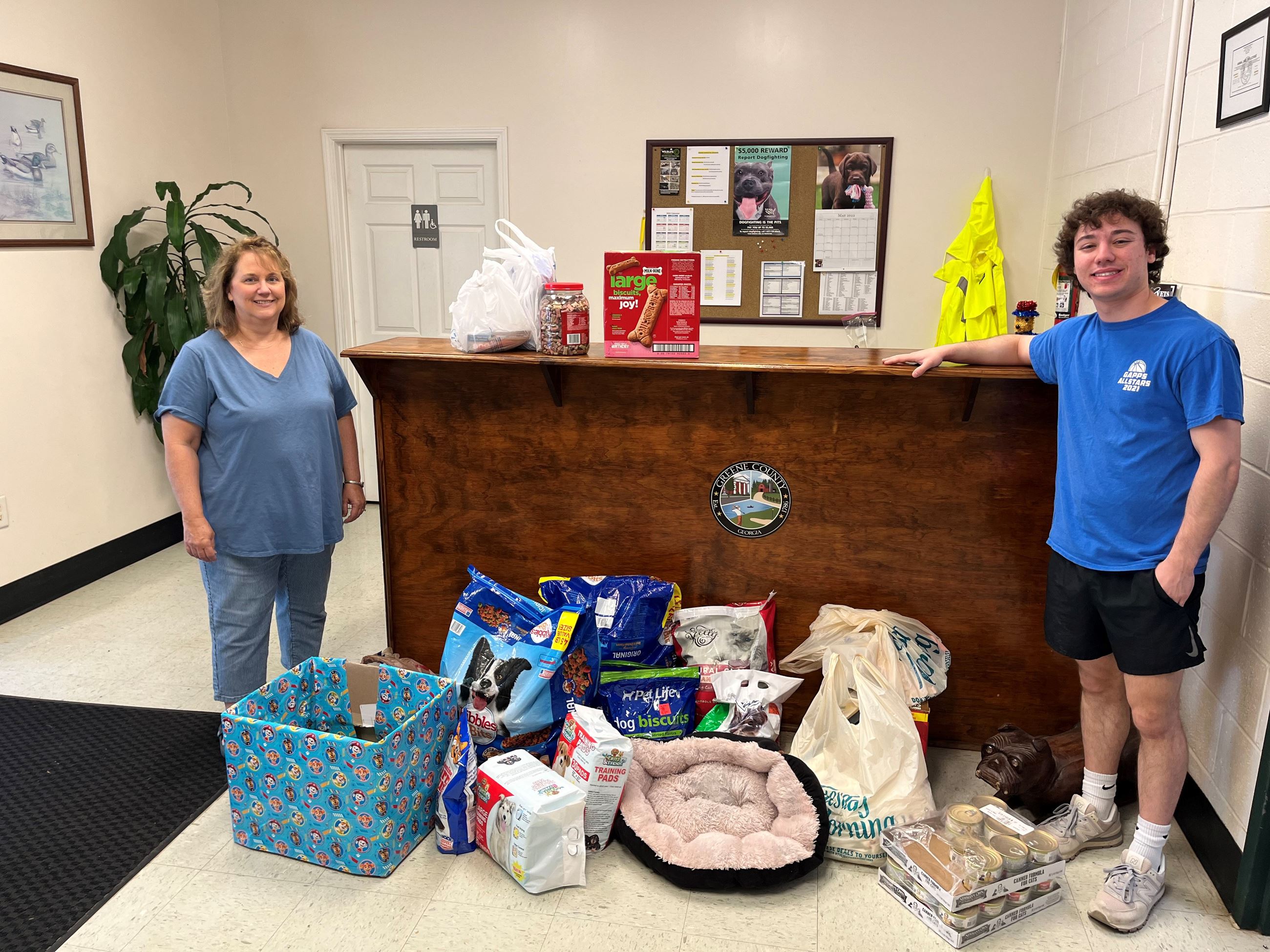 Woman and young man standing in front of a desk with donated items for Animal Control