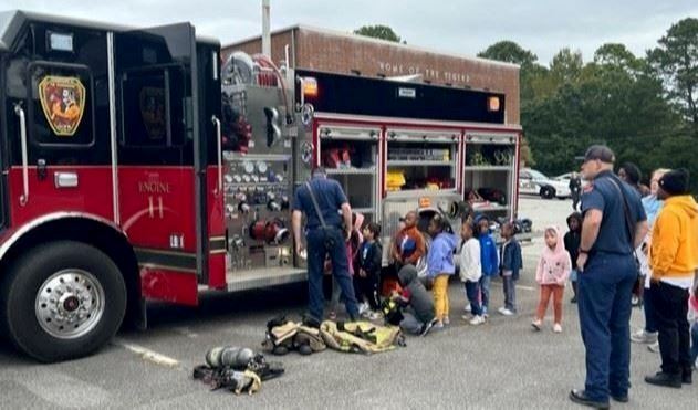 Fire truck with firefighters teaching preschool children.