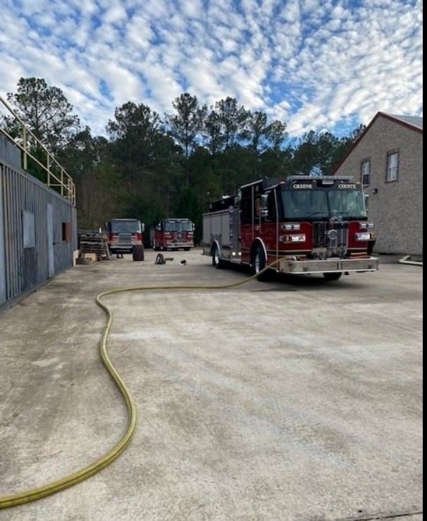 Three Fire Trucks and one has water hose stretched out