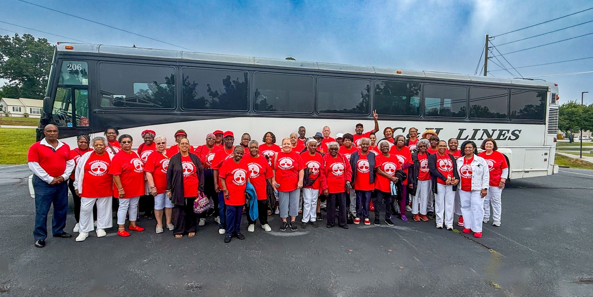 A group of people wearing white pants and red shirts standing in front of a bus.